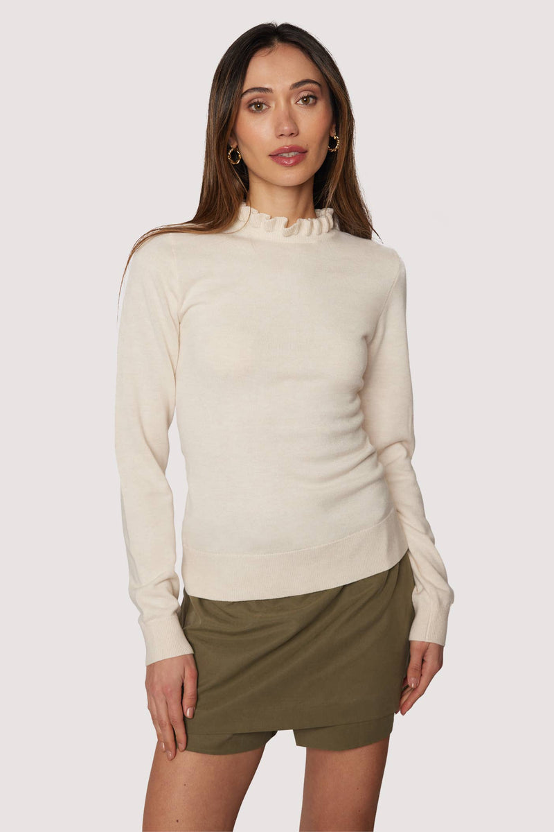 Woman wearing a beige sweater and green skirt on a white background